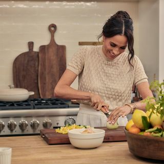 Meghan Markle cutting vegetable in kitchen