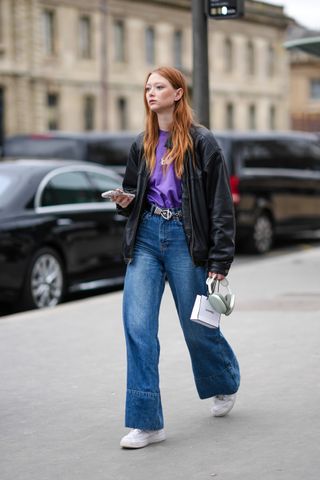 Woman wears white sneakers and jeans on her way to Paris Fashion Week.