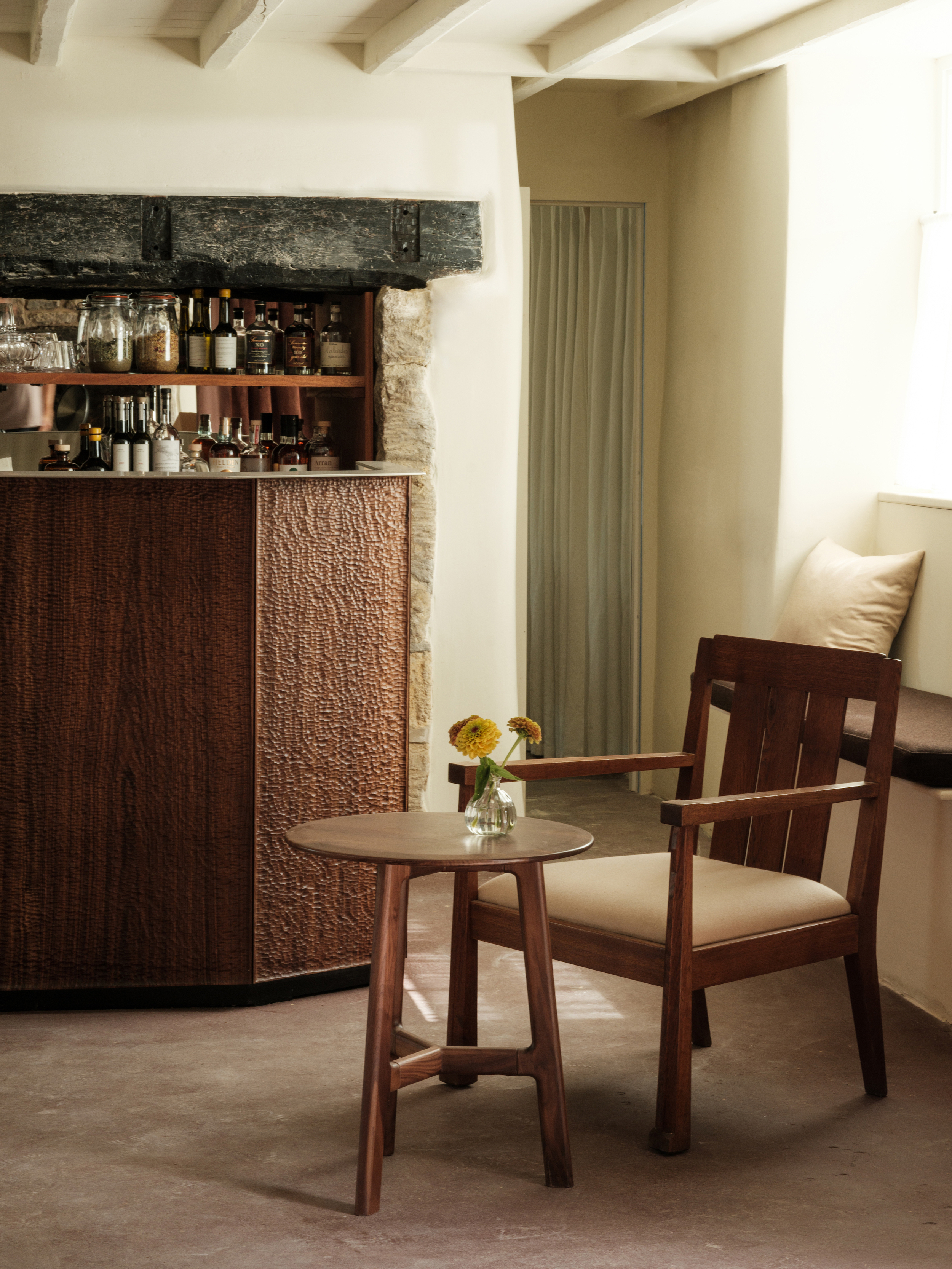 A series of shots depicting the interiors of a modernly renovated, old farmhouse in the countryside, mixing a rustic frame with plush textiles, textural surfaces, glass, wood, and chrome accents, and colorfully plated dishes.