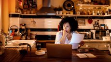 A woman looks over paperwork in her kitchen.