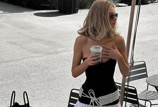 Elsa Hosk wearing a black-and-white drop-waist Helsa dress with a large belt at a coffee shop.