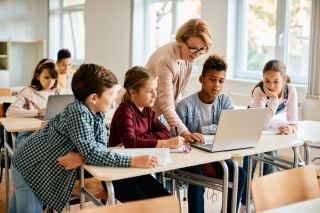 Elementary students having computer class with their teacher in the classroom.