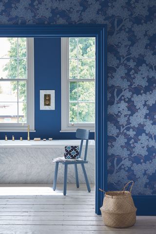 An example of blue bathroom ideas showing a bathroom with blue walls, blue wallpaper and blue woodwork white bath view from a bedroom through to the ensuite