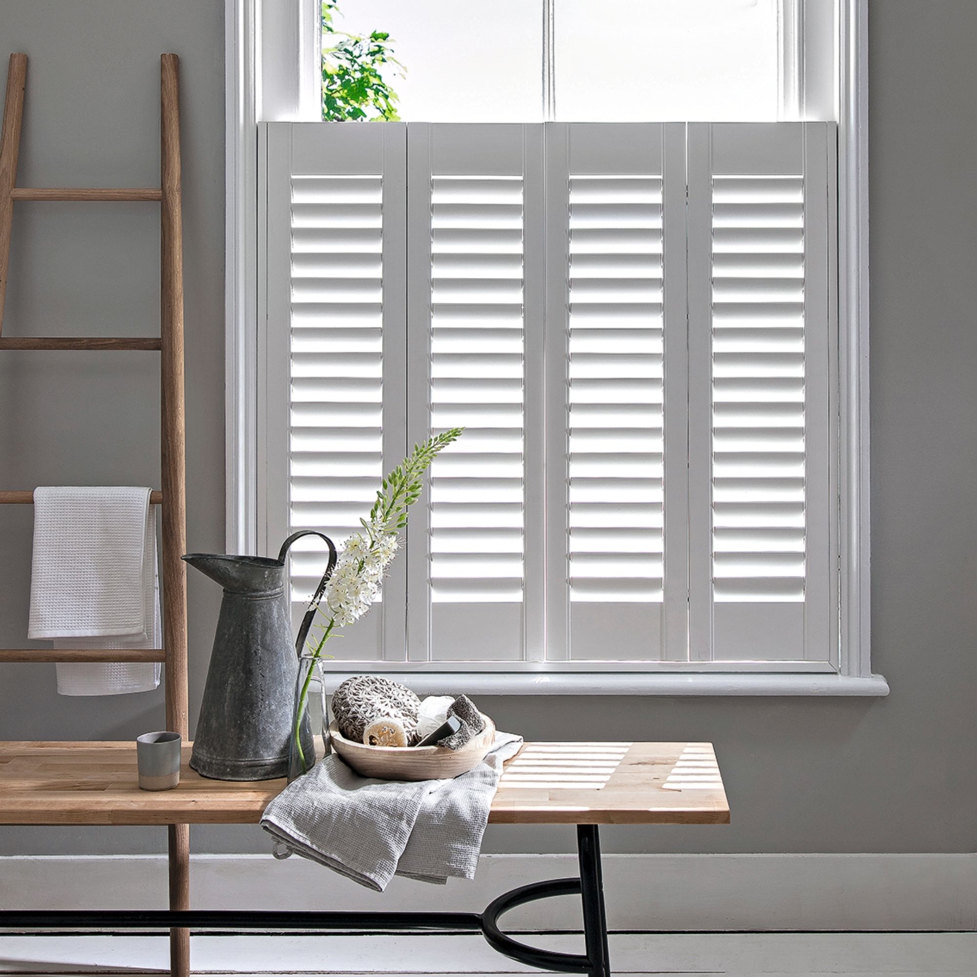 A neutral wall with white shutters shut at an angle