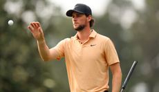 Pieters catches his golf ball whilst wearing an orange polo shirt