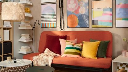 A colorful living room with a red couch, colorful block or stripey accent pillows, abstract wall art, a black floor lamp, and floating shelves