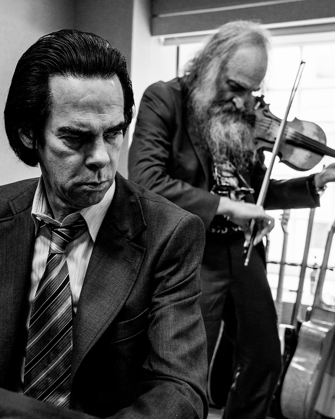 Nick Cave sat in front of Warren Ellis as he plays the violin