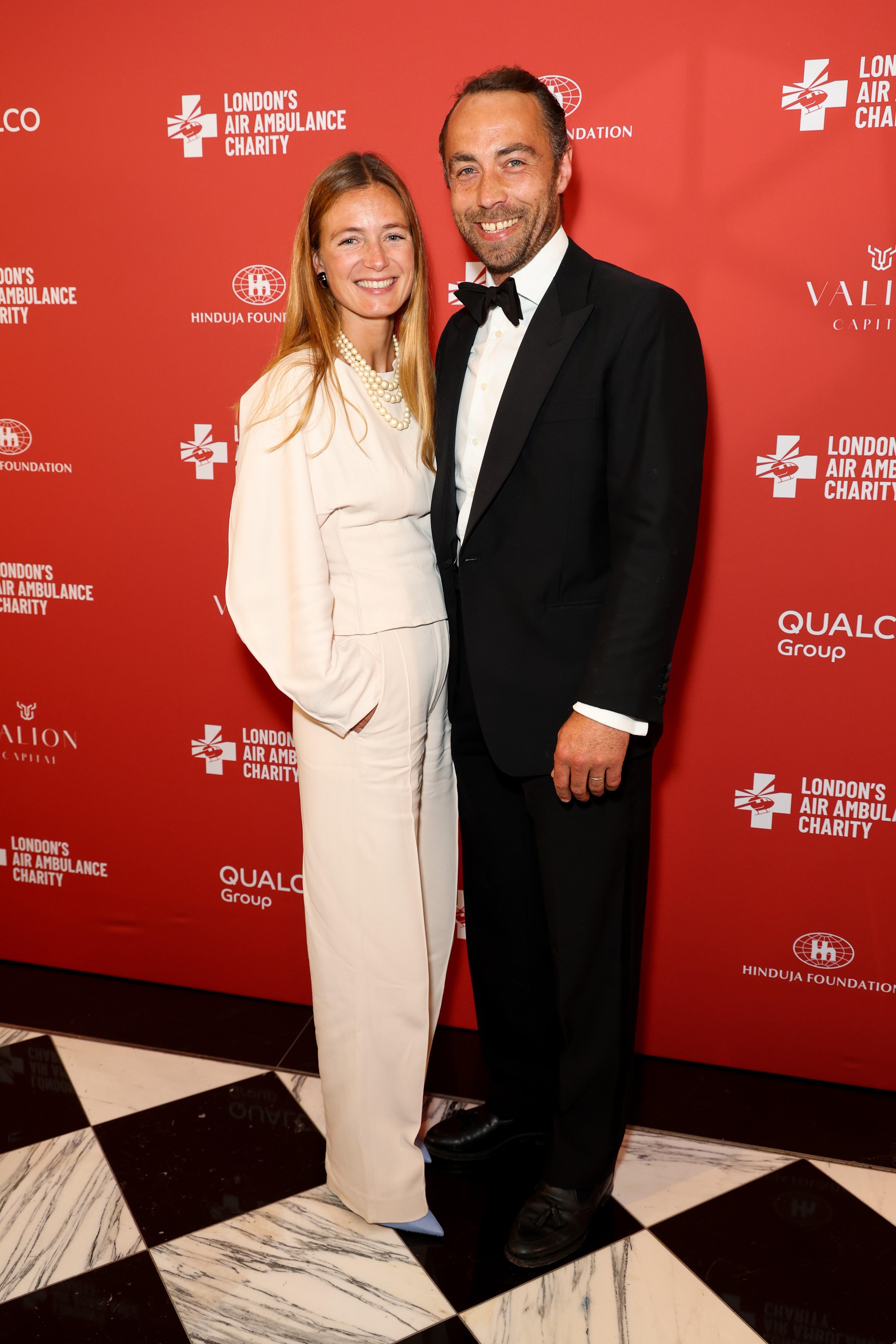 Alizee Thevenet wearing cream pants posing with James Middleton in a tux on the red carpet
