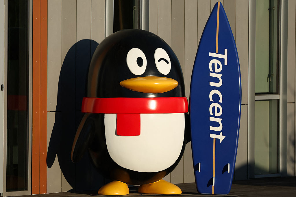 Emerging markets - penguin holding a surfboard bearing the Tencent logo