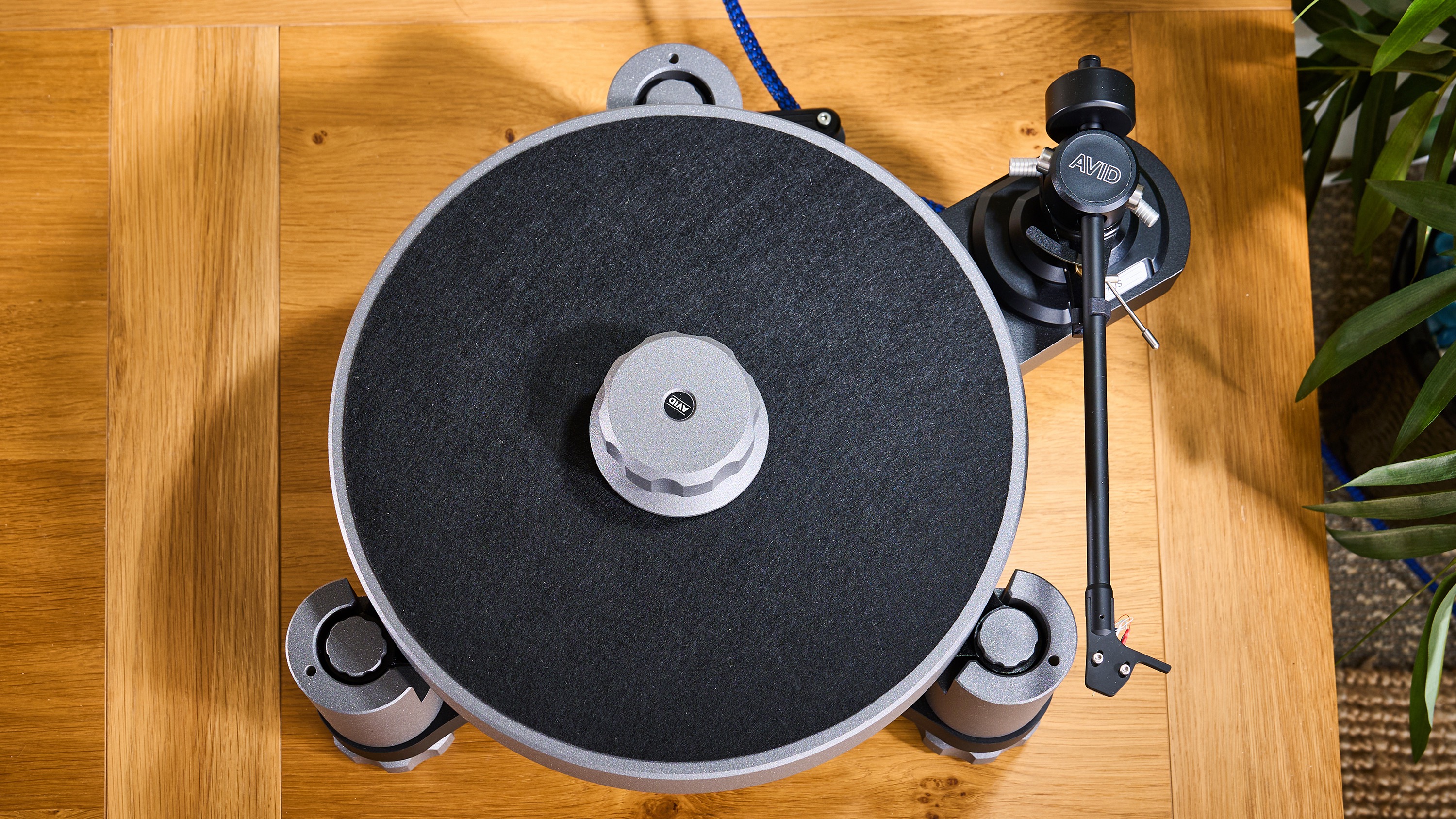 AVID Relveo turntable on wooden cabinet in warmly lit living room setting