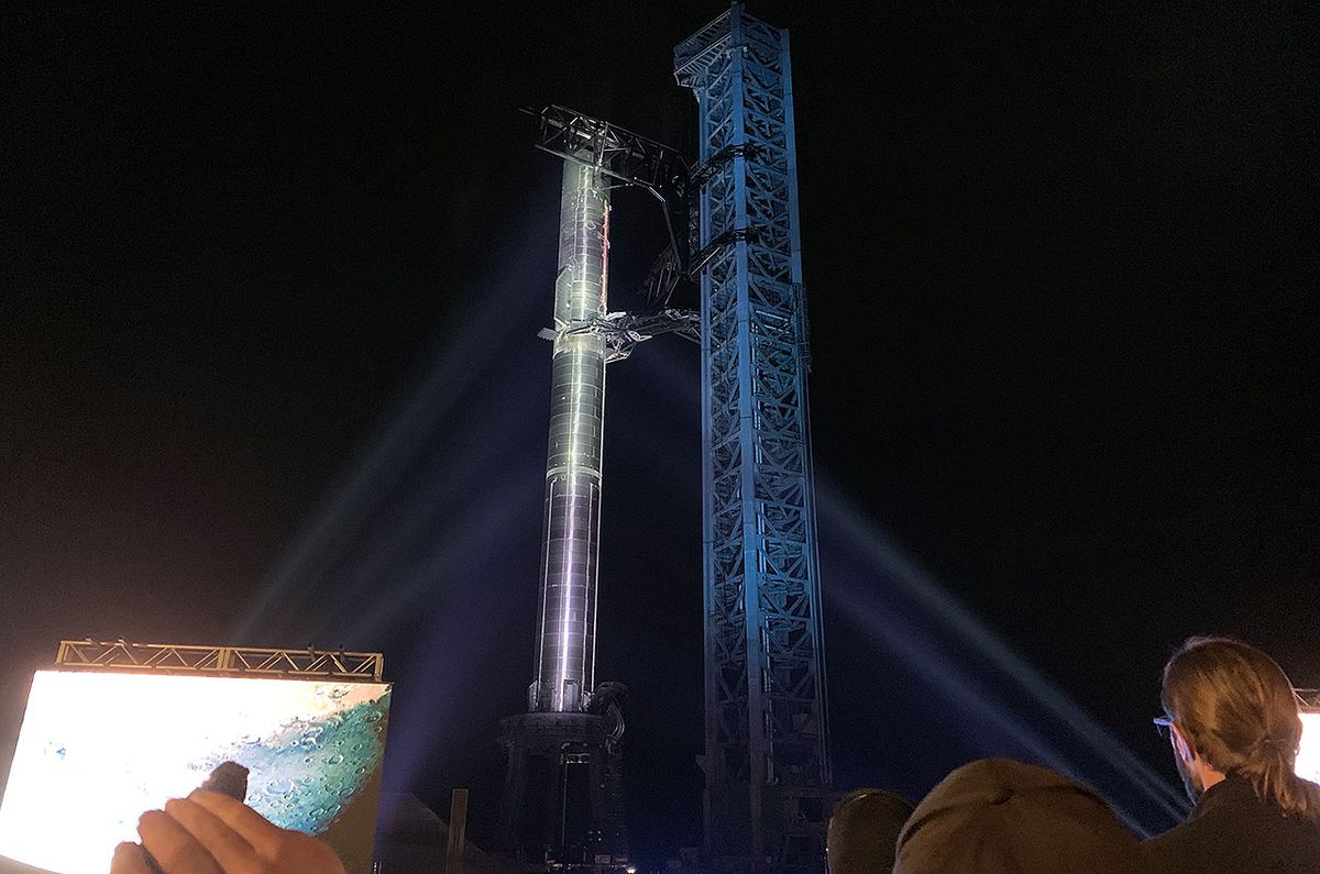 A SpaceX Starship stands fully stacked atop the launch and catch tower at the company&#039;s Starbase South Texas Launch Site in Boca Chica, Texas, on Thursday, Feb. 10, 2022. The vehicle and tower were lit for a media event with SpaceX CEO Elon Musk.