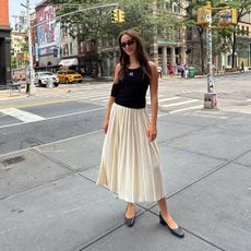 Liv Perez in NYC wearing a black tank top and white skirt
