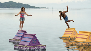 Liz Wilcox balances on a floating A-frame in the sea as Tim Spicer tumbles into the water on Survivor 46