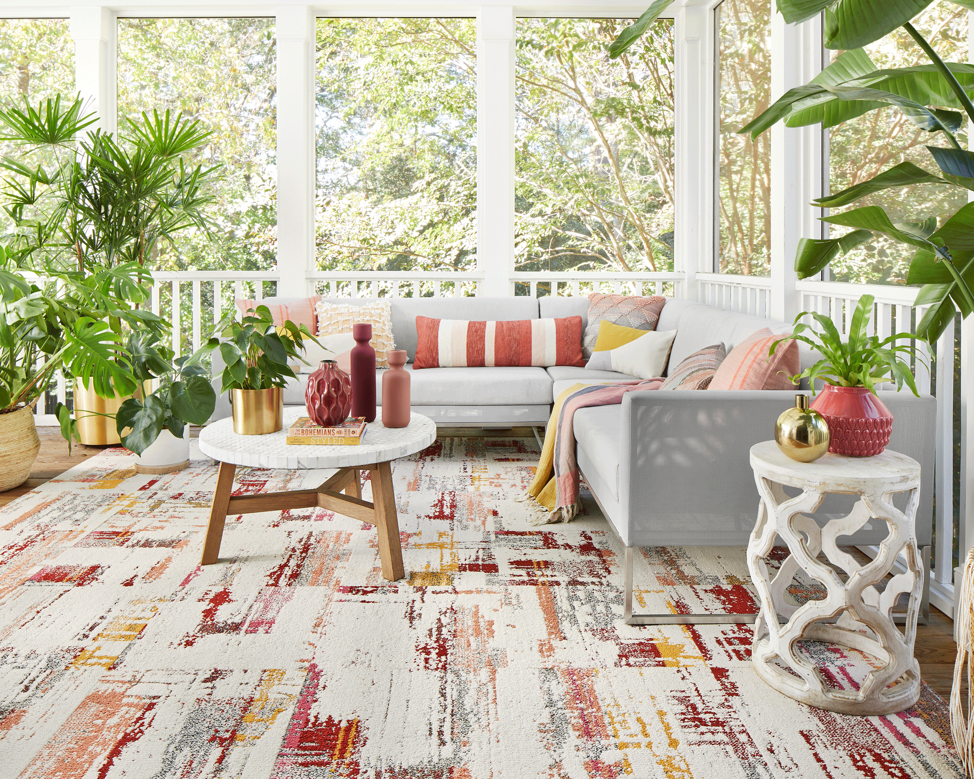 Colorful porch with terracotta and mustard rug, cushions, and soft accessories.