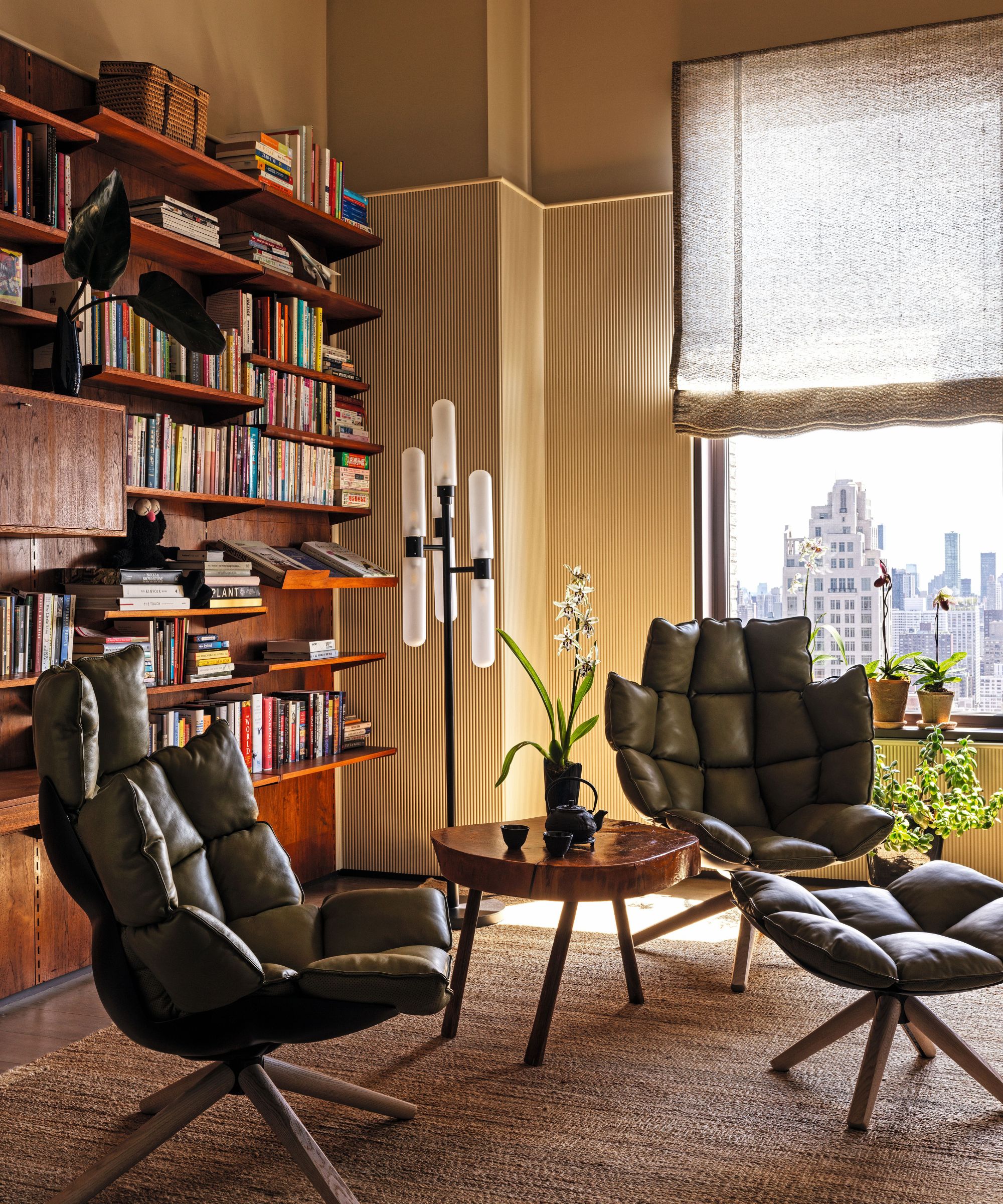 Butter yellow study with a vintage wooden bookcase on the wall and leather armchairs and matching footstool