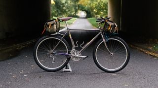 A grey mountain bike stands on an empty road beneath an underpass