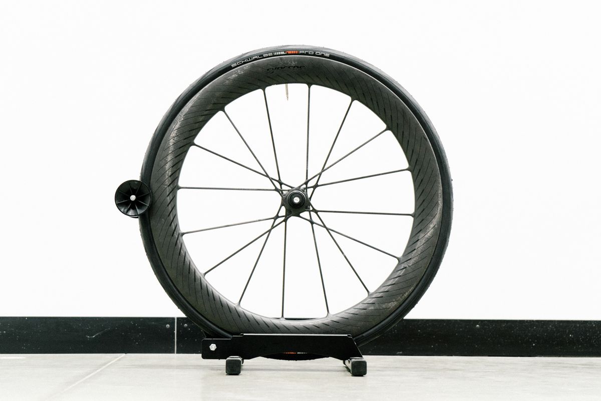 An aero road wheel stands against a white wall