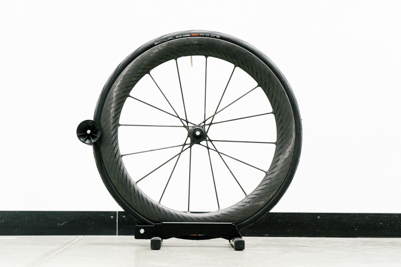 An aero road wheel stands against a white wall