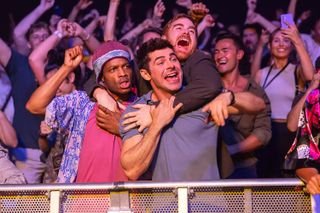 three men (jermaine fowler, zac efron, and andrew santino) wrap their hands around each other as they stand in the crowd at a concert