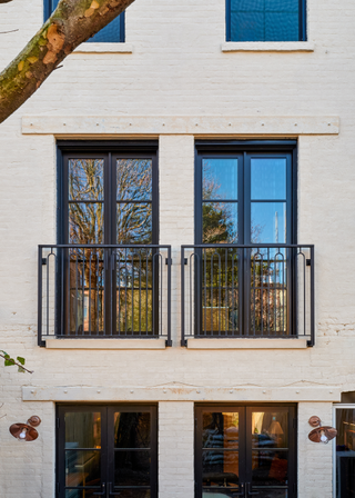 The back of a brownstone with iron railings across the balconies