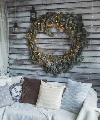 Sofa with fur cover, wool blankets and pillows with Christmas decoration on wall