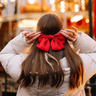 The back of a woman wearing a large red bow in her hair.