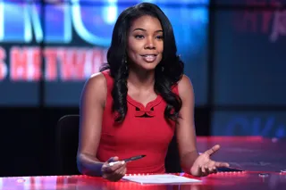 Gabrielle Union as Mary Jane Paul, sitting at a news anchor desk and holding a pen, in 'Being Mary Jane.'