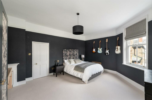 A black and white bedroom with a fireplace and guitars on the wall