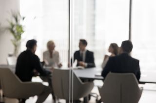 Group of businesspeople negotiating gathered in modern conference room