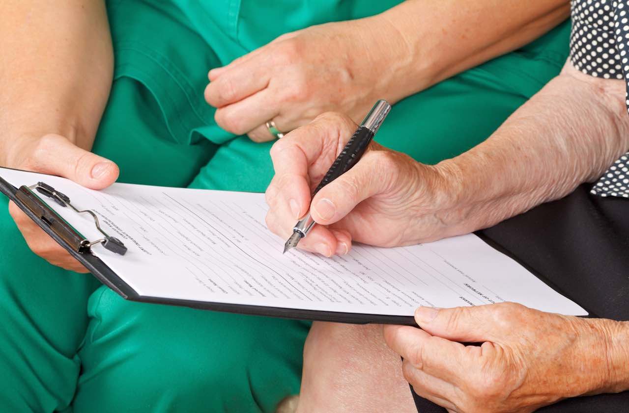 A senior woman&amp;#039;s hand signing a document