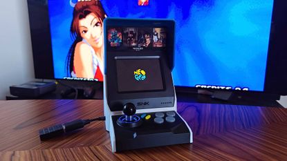 Neo Geo Mini arcade machine with Mai on screen in backdrop.