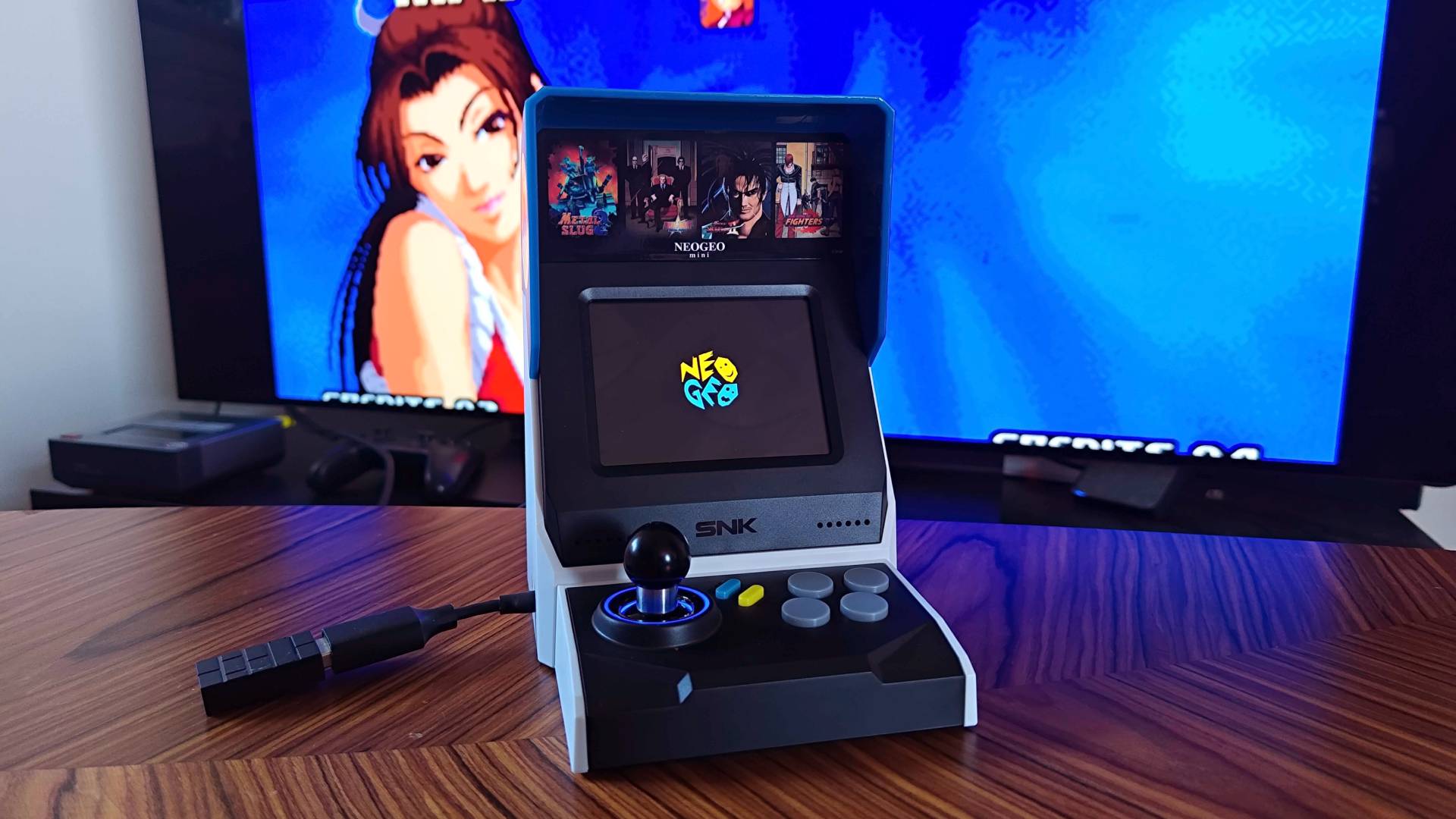 Neo Geo Mini arcade machine with Mai on screen in backdrop.