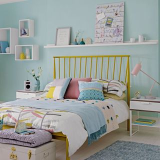 pale blue bedroom with white shelving and yellow bedframe with pink and blue bedding