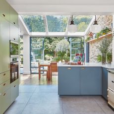 A modern kitchen diner with access to garden, skylights and mid-blue cabinetry
