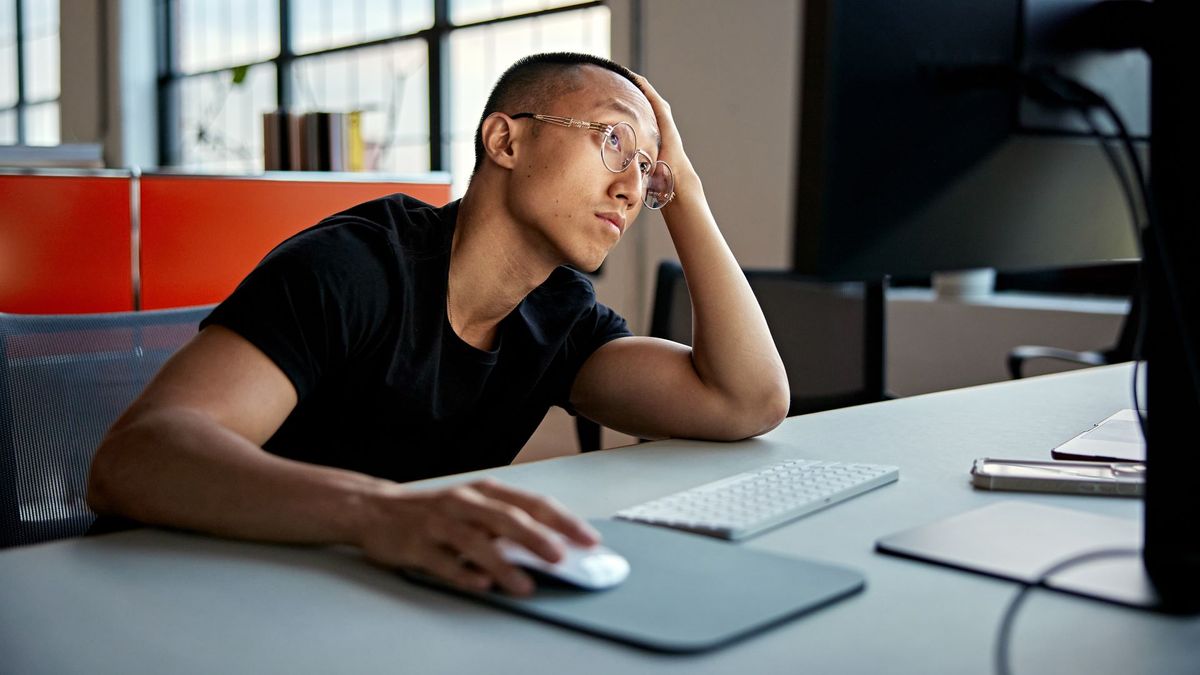 A man looking bored using a desktop computer