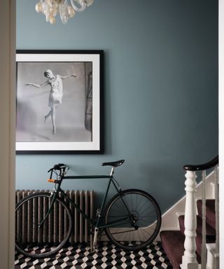 hallway with muted blue wall, black and white floor tiles and bike