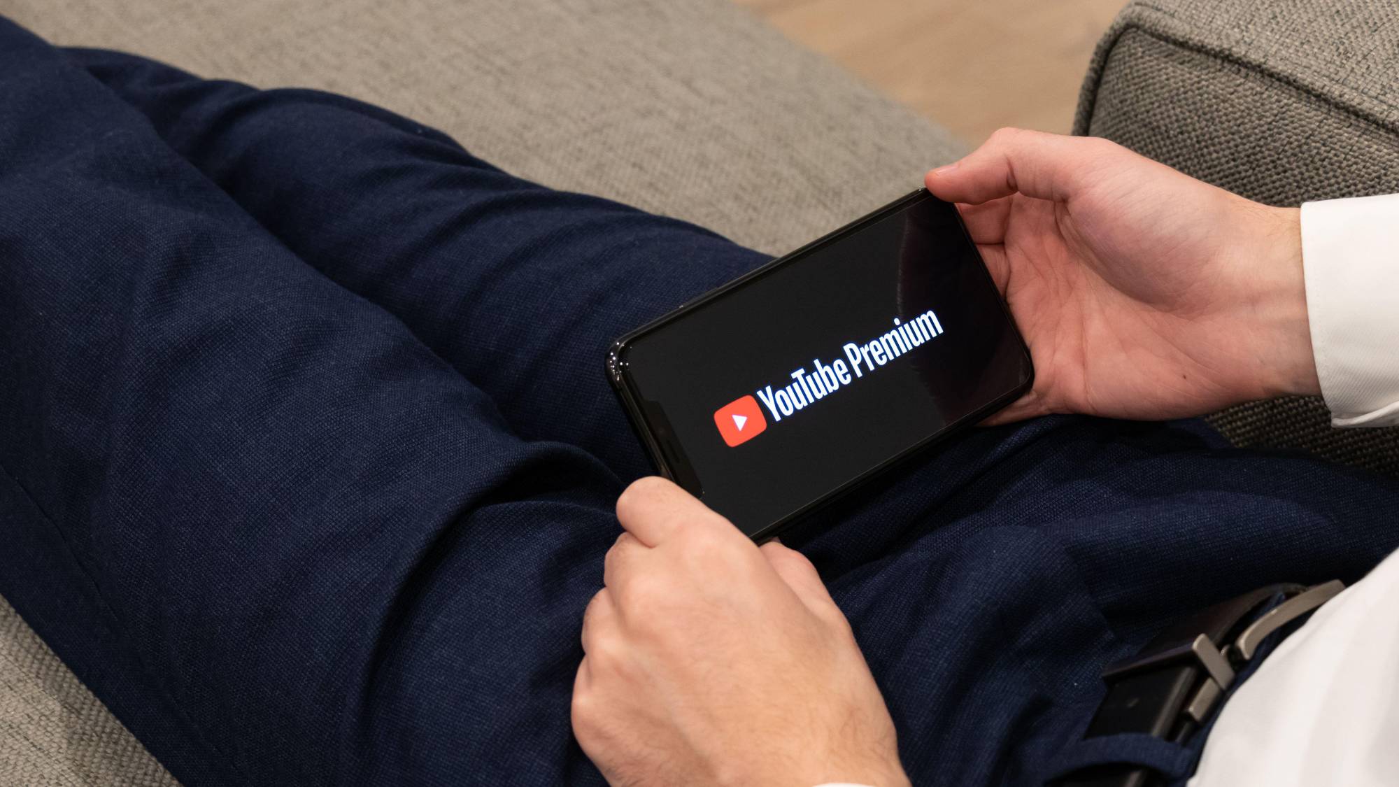 YouTube Premium logo on a smartphone held in two hands