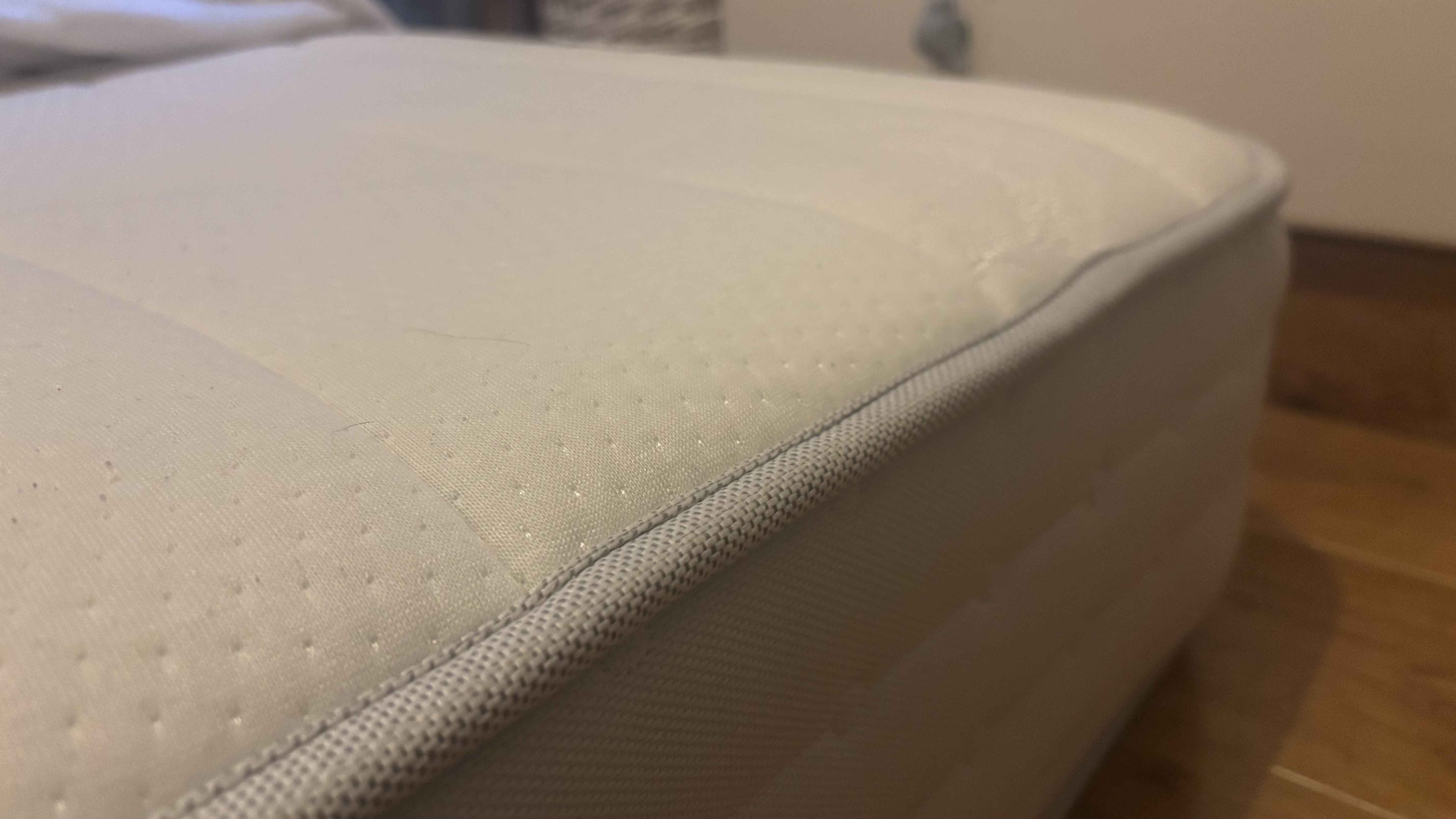 A close up look at the corner of a spring mattress on the floor.