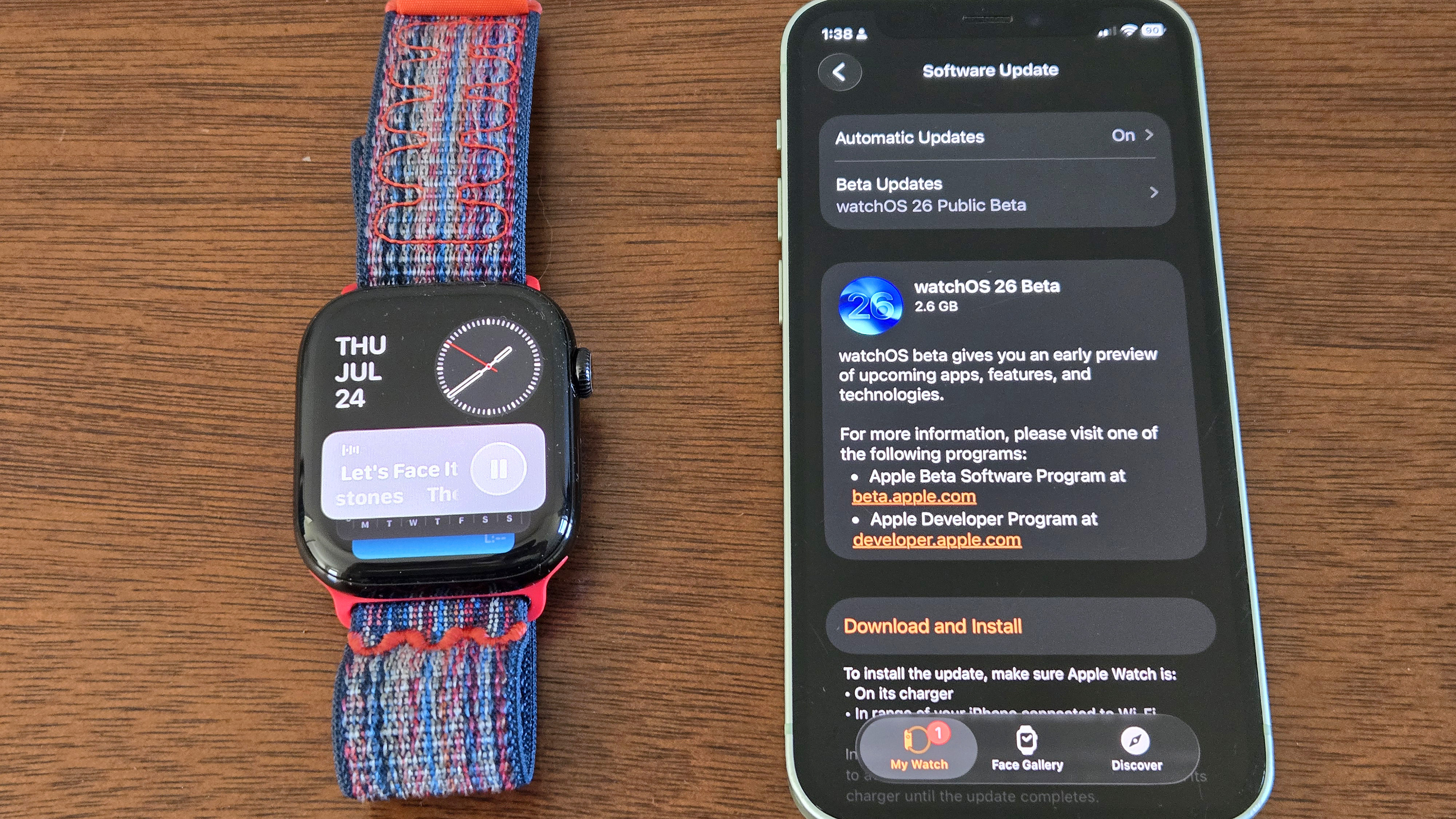 Close-up of the installation process for watchOS 26 showing an Apple Watch Series 10 and iPhone 12 Mini