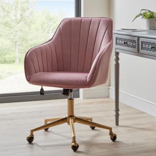 A pink velvet chair with gold legs