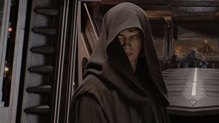 Still from a Star Wars movie. Here we see an evil-looking Anakin Skywalker, his brown Jedi robes pulled up an hiding most of his face.