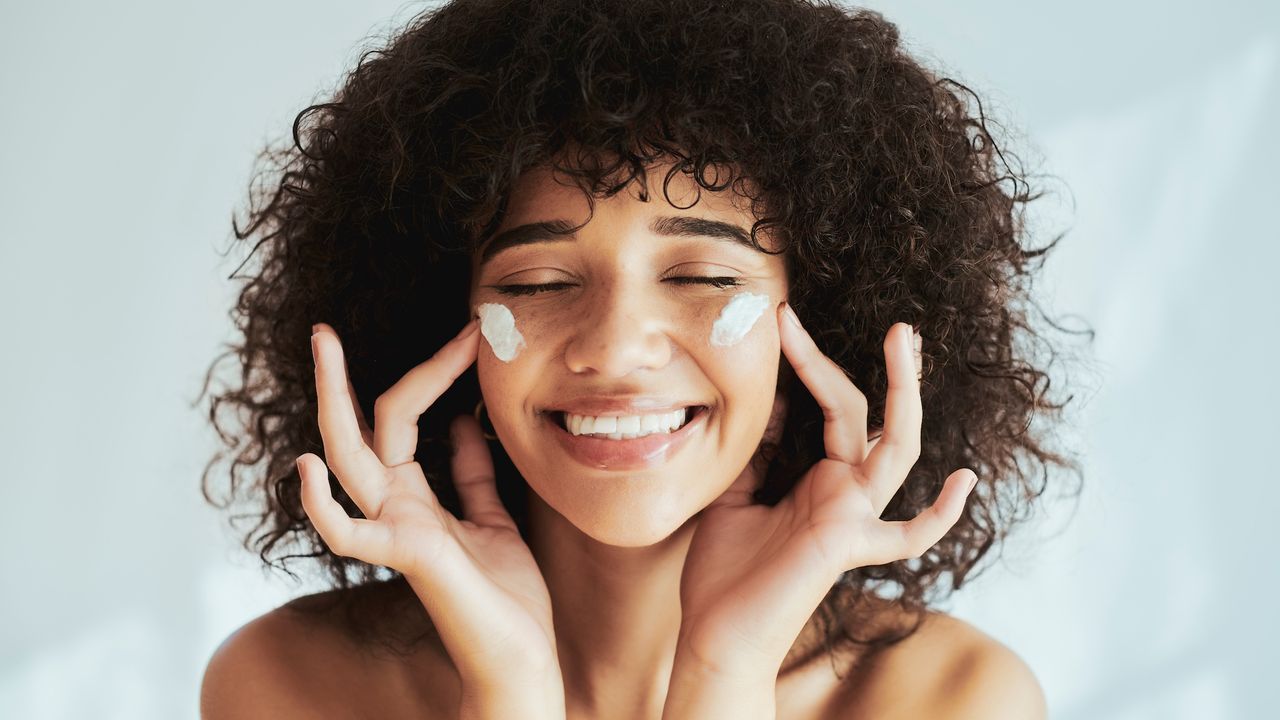 image of a smiling woman with cream on her cheeks - Best moisturiser