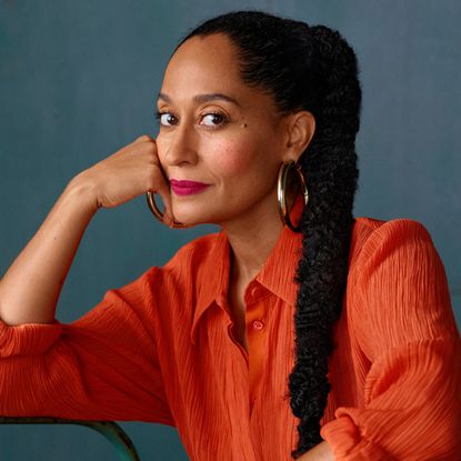 Tracee Ellis Ross wears an orange shirt and has a long ponytail