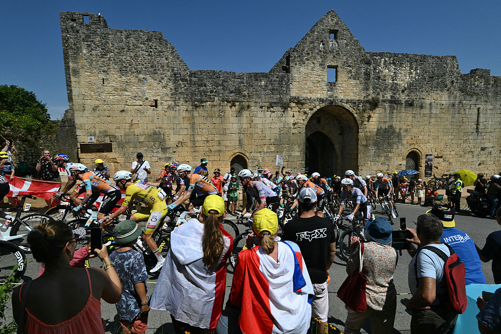 The pack of riders (peloton) cycles in the town of Domme during the 8th stage of the 113th edition of the Tour de France cycling race, 180,4 km between Perigueux and Bergerac in southwestern France, on July 11, 2026. (Photo by Jeff PACHOUD / AFP)