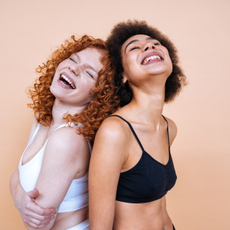 beauty image of two young women with different skin and body posing in studio for a body positive photoshooting. Mixed female models in lingerie on colored backgrounds
