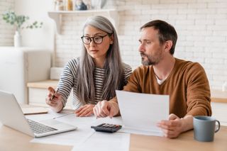 A couple discussing their finances, looking at a laptop.