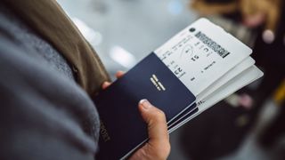 Someone holding a passport with two boarding passes inside it