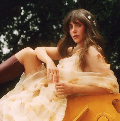 Alison Brie outdoors wearing a floral dress and tall boots