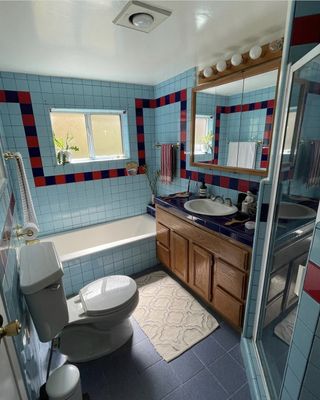 A dated bathroom with red and blue tiles with a strikethrough pattern