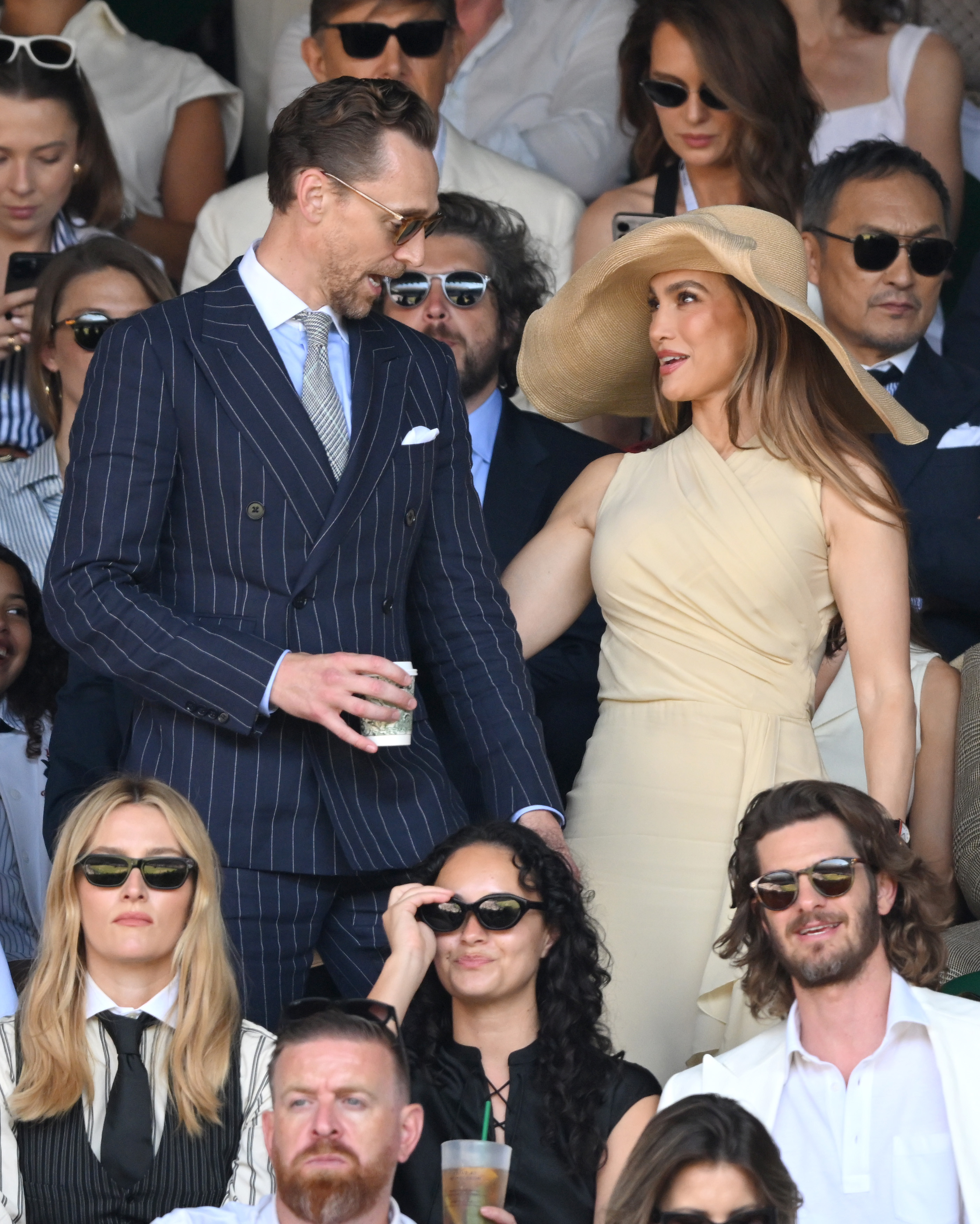 Jennifer Lopez attends Wimbledon on July 12, 2026 wearing a massive raffia hat and a dress from Ralph Lauren, joining Tom Hiddleston who wears a navy pinstripe suit